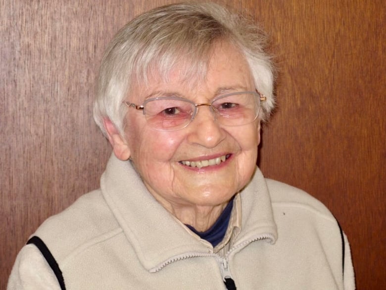 And old woman with short, cropped white hair smiles at the camera