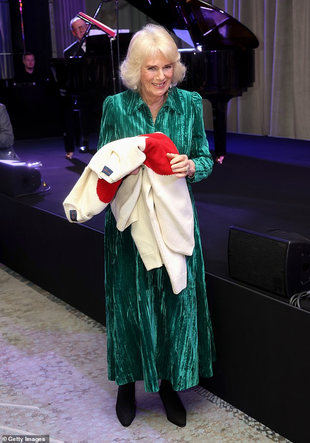 Camilla smiles as she holds gifts of Valentine's Day jumpers with red hearts displayed on them