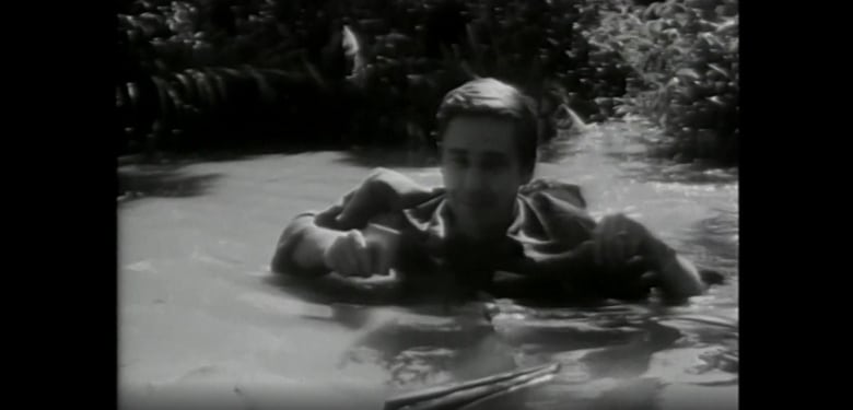 A person wades through chest-high water in this black and white photograph.