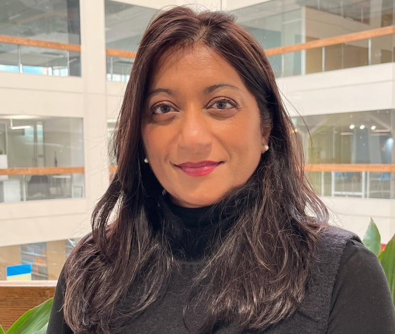 A woman smiles while facing the camera.