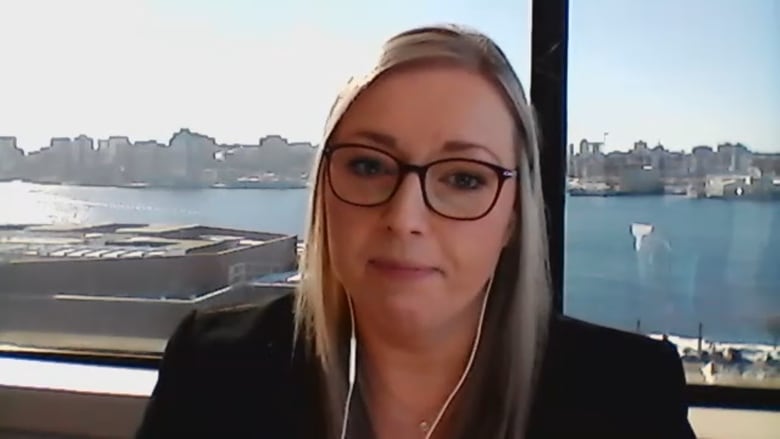 A blonde woman is seeing wearing a pair of black glasses.