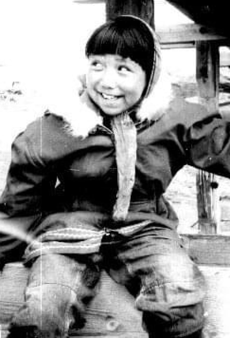 A black and white photo of a young girl, smiling. 