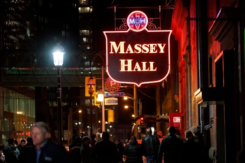 Lit up sign that says Massey Hall over a busy nighttime street