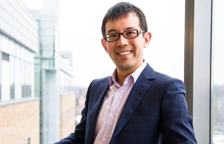 A man in glasses smiles at the camera.