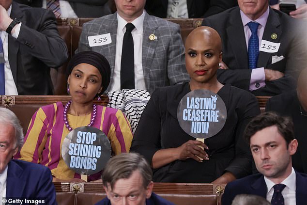 Rep. Ilhan Omar (D-Minnesota) (left) and Rep. Ayanna Pressley (D-Massachussetts) (right) hold up signs supporting a ceasefire in the Middle East