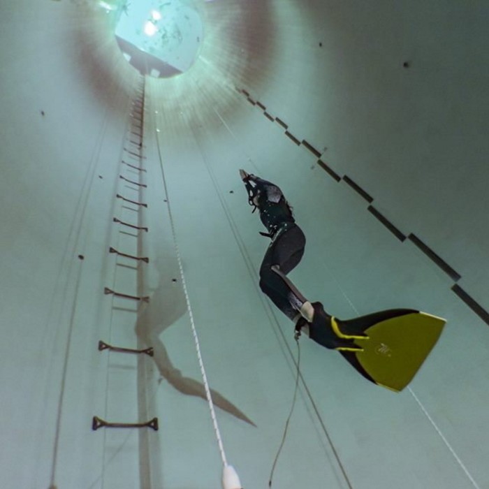 A diver in wet suit and flippers swims back towards the surface