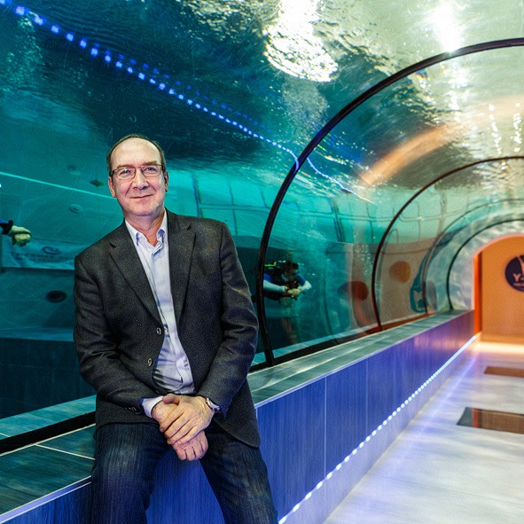 A man in suit sits in a transparent underwater tunnel