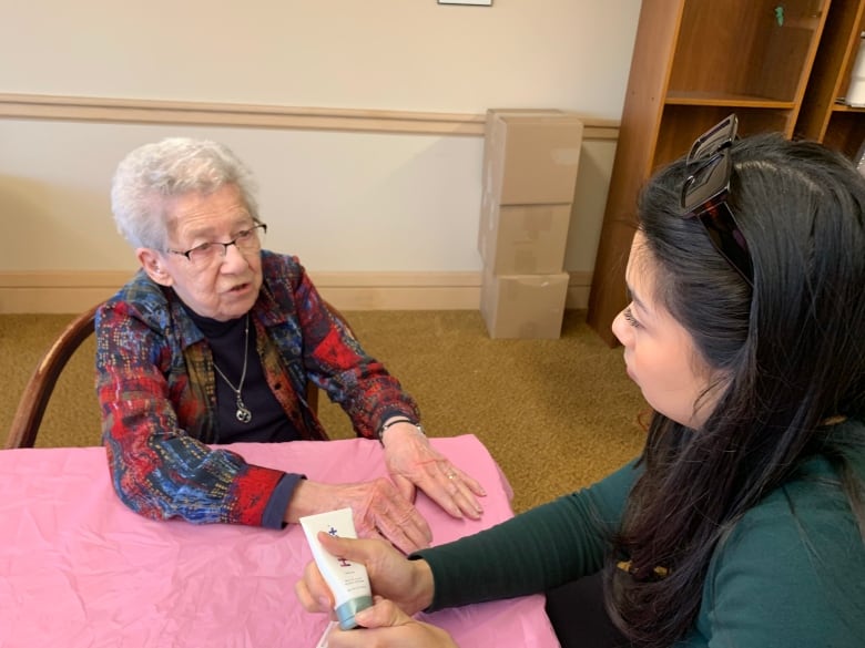 A young woman paints the nails of an older lady. 