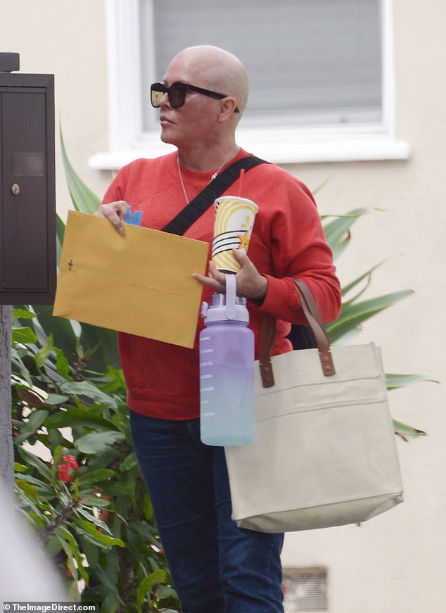 She had her hands full with a purple and light blue motivational water bottle, to help her stay hydrated, a canvas tote bag and an iced beverage from Carl's Jr.