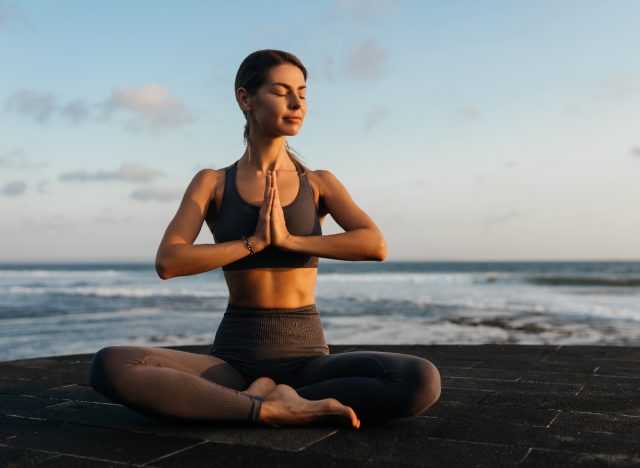 woman meditating at the beach, coping with being betrayed by a best friend