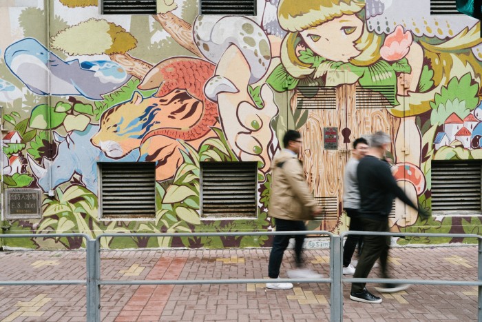 People walk in front of a wall like a cartoon zoo has run loose