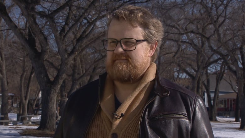 A man stands in a snowy park.