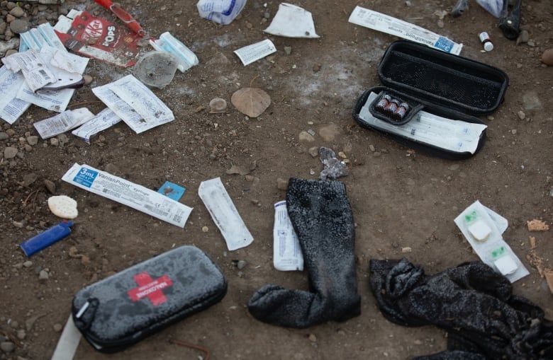 Naloxone kits and other debris lay on the ground. 