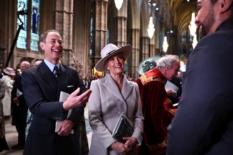 Two people laugh as they speak with other people inside a large church.