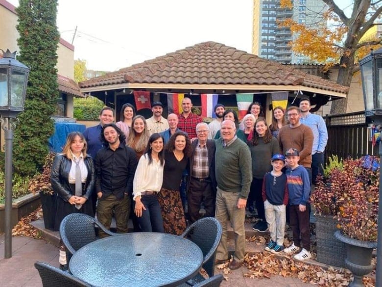 Twenty six members of a family pose for a photo outside to celebrate the great grandfather's 90th birthday. 