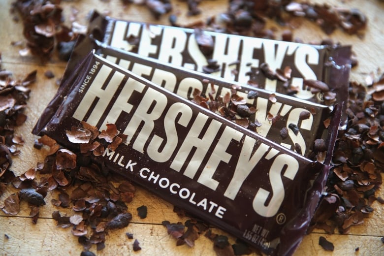 Three Hershey's chocolate bars rest on some chocolate shavings. 