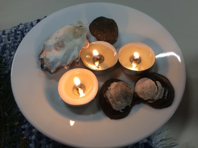 A bowl with three tea light candles and some clam shells. 