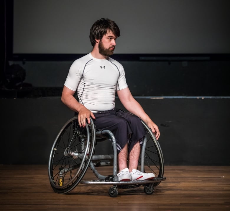 A man sits in a wheelchair on a stage.