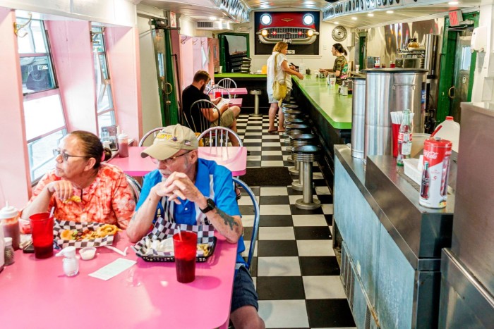 An elderly couple sit inside a diner