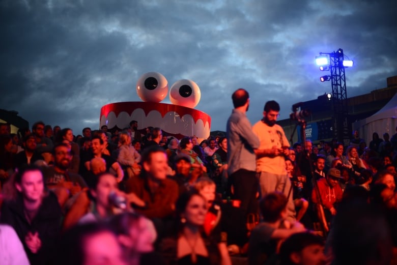 A giant statue of teeth and a pair teeth behind a crowd.