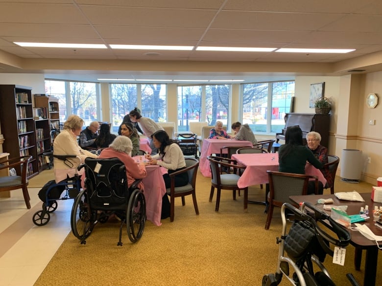 Young and old gather in a retirement residence room.