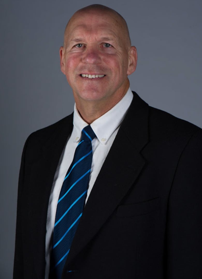 David Behm smiles at the camera, wearing a suit and tie.