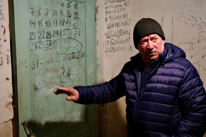 Ivan Polhuy shows the Financial Times a room in the Yahidne school basement where the names of seven people shot to death by Russian soldiers and 10 others who died from the harsh conditions are written on a wall