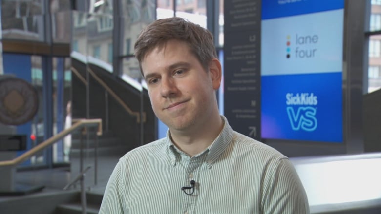 A man with a green striped shirt inside SickKids hospital.