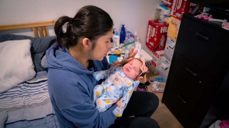 A mother in a blue sweatshirt holding her baby.