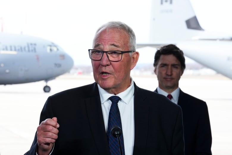 Prime Minister Justin Trudeau stands behind National Defence Minister Bill Blair as they hold a press conference on Canada's new defence policy at CFB Trenton in Trenton, Ont. on Monday, April 8, 2024.