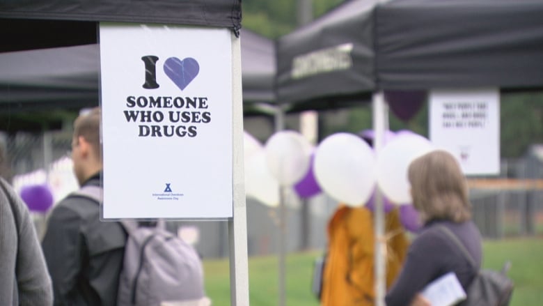 A white sign at a New West Naloxone training event that says "I love someone who uses drugs" but the love is represented by a purple heart. 