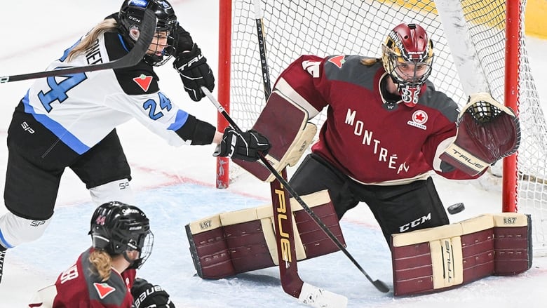 A Toronto women's hockey player in a blue, black and white jersey pokes her stick in the direction of a Montreal goalie to try to redirect a shot during a PWHL game on April 20, 2024 in Montreal.