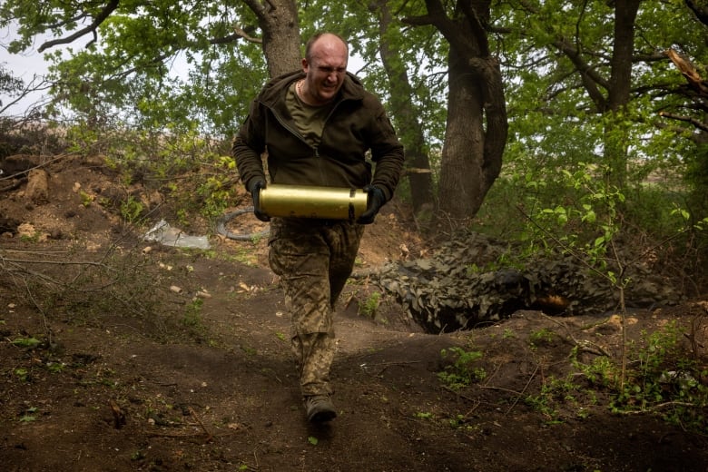 A Ukrainian soldier is seen carrying an artillery shell near the outskirts of Kupiansk, Ukraine.