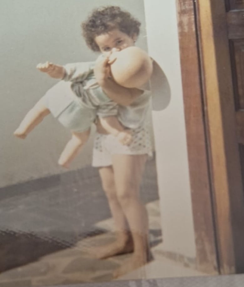 A young girl kisses a doll in this old photo.