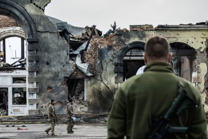 A soldier standing in front of a destroyed railway station in Kostiantynivka