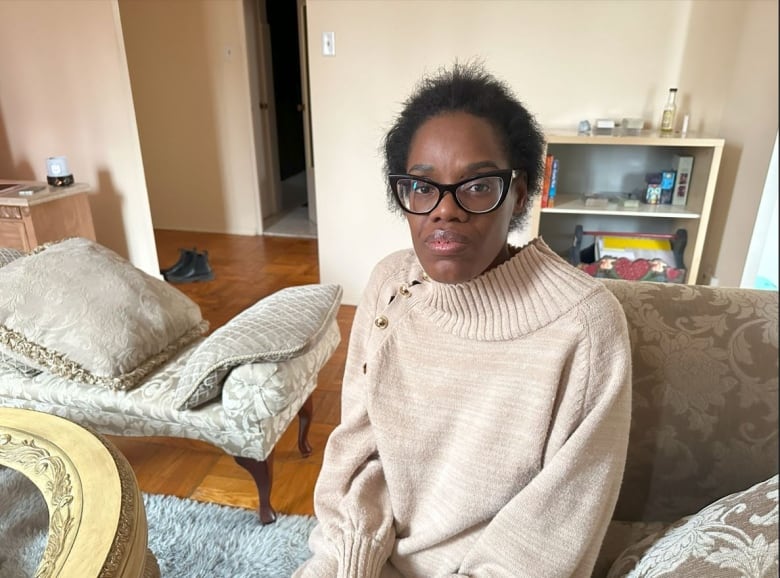 A person sits on a couch in a living room.