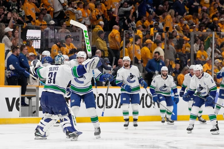 Hockey players celebrate with sticks in the air.