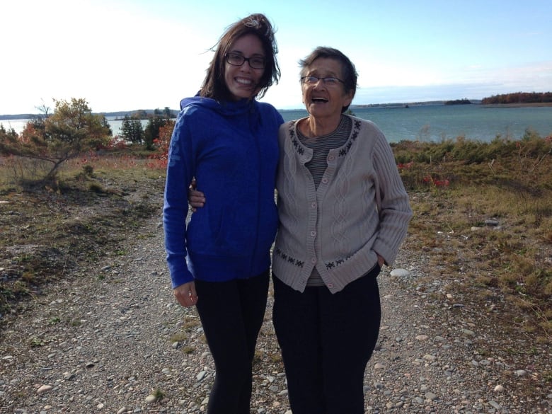 A younger woman embraces an older woman with a large lake in the background