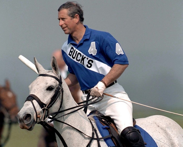The then Prince Charles playing polo at Cirencester Polo Club.  The prince Is wearing a blue polo shirt with the team name “Buck’s” written across it.