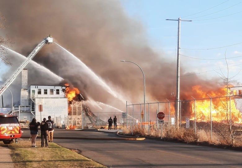 A firefighter showers a building with water from a cherry picker.