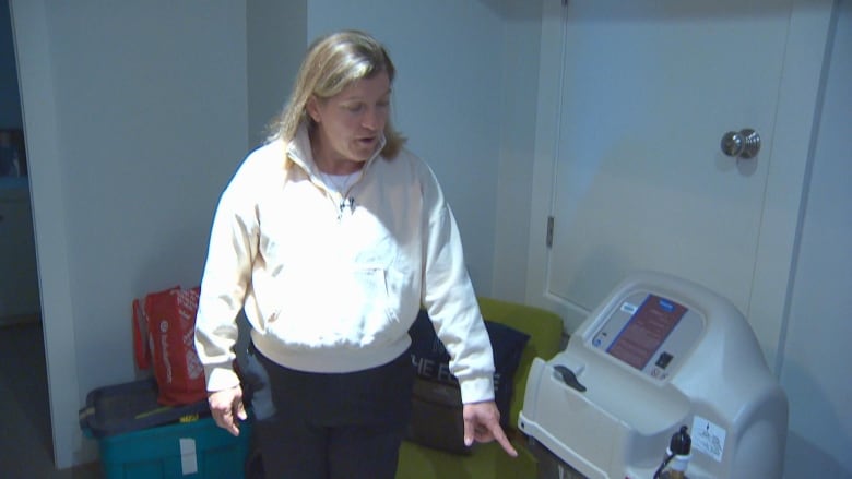 Farrell Eckman, who has been diagnosed with pulmonary fibrosis following two bouts with COVID, shows an air compressor that is kept in her home.