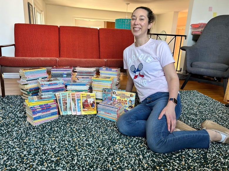 A smiling woman next to stacks of books