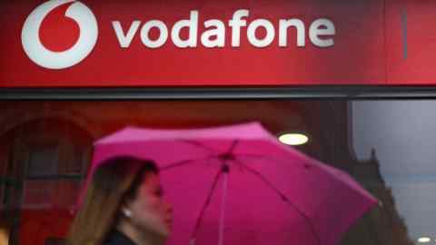 A pedestrian passes a Vodafone store in west London