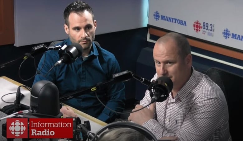 Two men sit at a desk with microphones