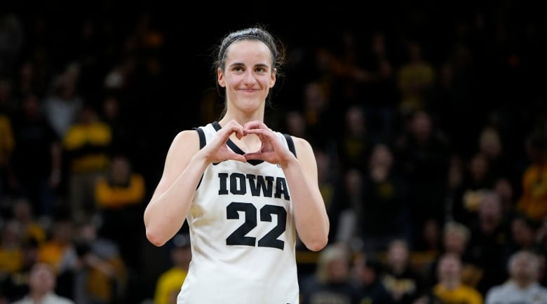 An athlete in a basket jersey that says Iowa 22 makes a heart-shaped gesture with her hands