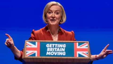 A woman stands at a podium that features a Union Jack and the slogan ‘Getting Britain Moving’