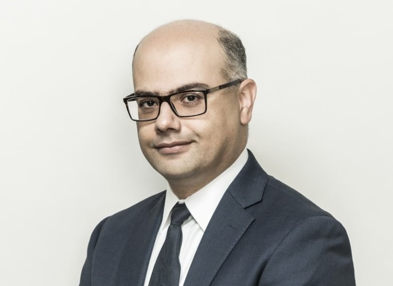 Portrait of a bald man with glasses wearing a suit