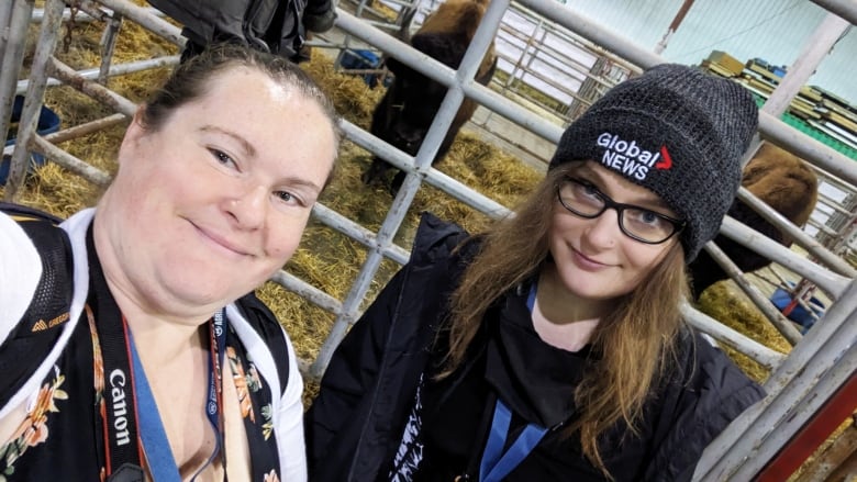 Two smiling women pose for a selfie in a barn.  