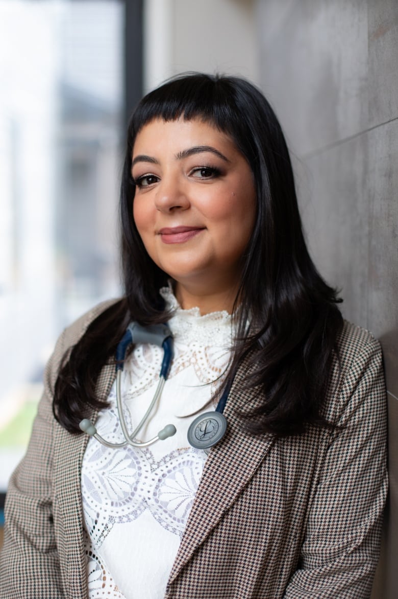 Woman with long, dark hair, white shirt and suit jacket.