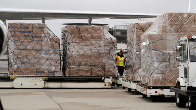 Wrapped boxes stacked high are shown on conveyor like transport in an outdoor photo.